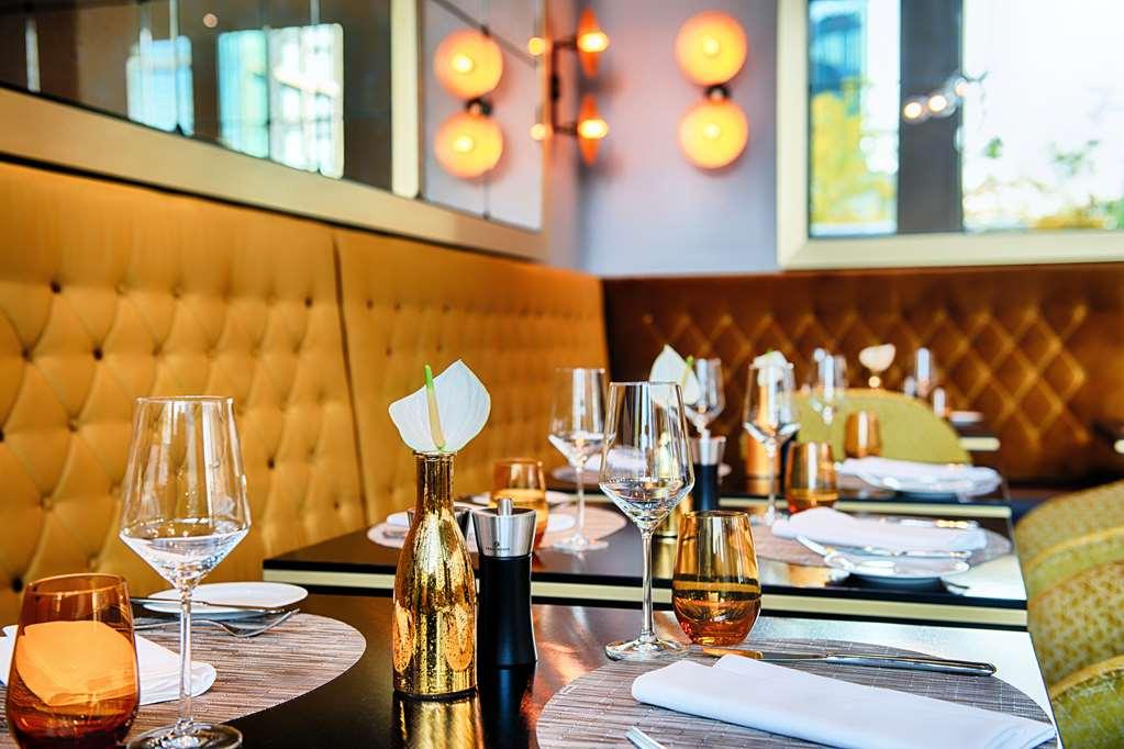 Steigenberger Hotel Am Kanzleramt Berlin Restaurant photo The photo shows an elegant dining area in a restaurant. The tables are set with fine dining essentials, including wine glasses, water glasses, and neatly arranged napkins. The seating features plush, tufted golden leather upholstery against a backdro