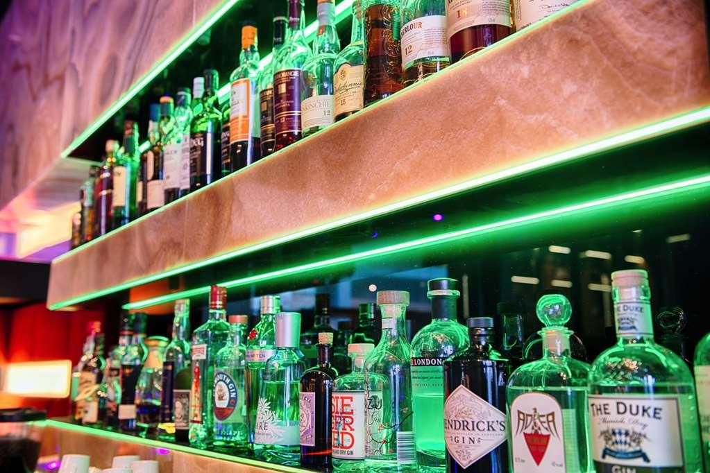 Steigenberger Hotel Am Kanzleramt Berlin Restaurant photo The photo depicts a well-organized display of various bottles of alcoholic beverages arranged on shelves. The shelves are illuminated with green lighting, enhancing the visual appeal of the setup. The bottles include a mix of spirits such as gin, whi